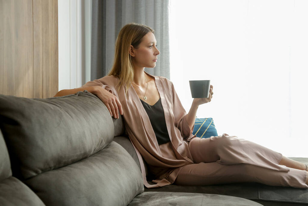 Žena v saténovém obýváku odpočívá a sedí v obývacím pokoji - Fotografie, Obrázek