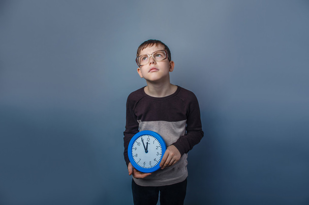 Європейський дивлячись хлопчик десяти років проведення настінні годинники reflecte - Фото, зображення