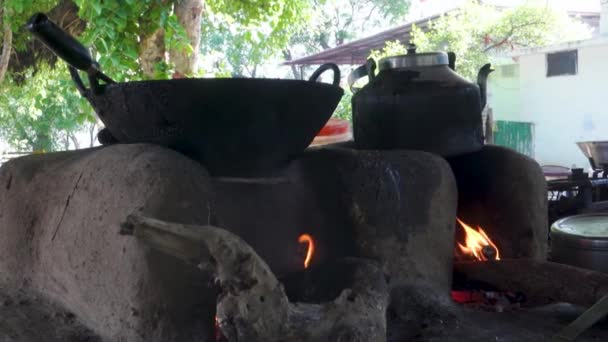 Piękny tradycyjny kominek wykonany z gliny z palącym się drewnem i żeliwnych naczyń na szczycie. Uttarakhand Indie. - Materiał filmowy, wideo