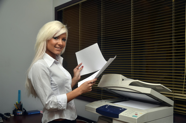 mooi meisje scant documenten op kantoor - Foto, afbeelding