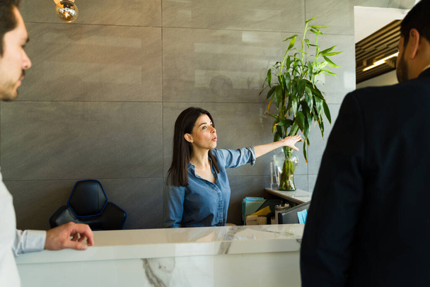 Portrait of a Caucasian receptionist greeting some clients and giving them directions - Photo, Image