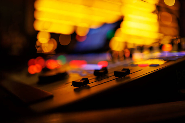 Console mixer de som moderno com botões coloridos e controles deslizantes, definido contra o pano de fundo de um local de música ao vivo. - Foto, Imagem