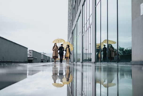 Colleghi di lavoro che camminano con gli ombrelloni in una giornata piovosa in città. - Foto, immagini