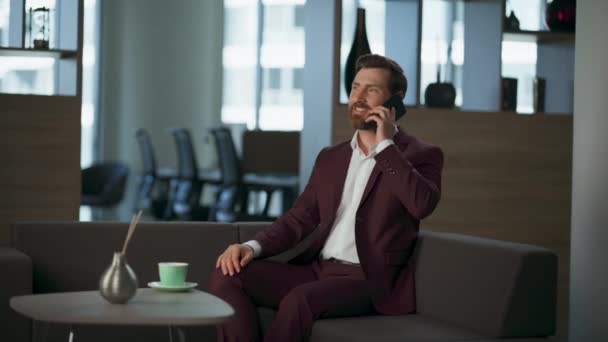 現代的な快適なオフィスの大きい窓で電話をするビジネスマン. ホールで金融作業計画の携帯電話について議論する陽気なひげ起業家マネージャー. 成功した ceo man プロ企業コンセプト - 映像、動画