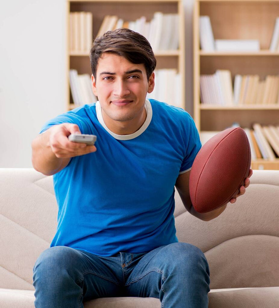 Muž, který doma sleduje fotbal, sedí na gauči. - Fotografie, Obrázek