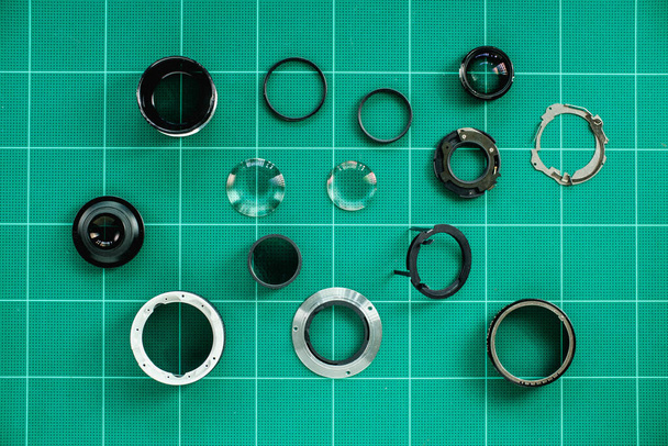 分解されたカメラ レンズおよびレンズは修理およびクリーニングを待っている緑のサービス テーブルに置かれる用具装置を修理します - 写真・画像