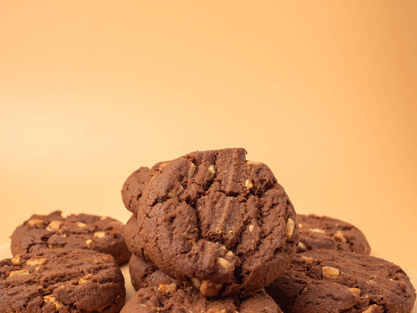 Chocolade, rijke koekjes met contrasterende witte chocoladechips op een oranje achtergrond. Koekjes met witte chocolade close-up. - Foto, afbeelding