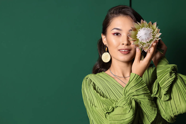 Mladý asijské žena s krásný protea květina na zeleném pozadí - Fotografie, Obrázek
