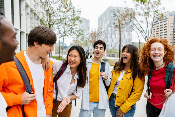 Молодая группа подростков разговаривает после старших классов. Разнообразные студенты тысячелетия сближаются и зависают на городской улице. Образование и молодежь. - Фото, изображение