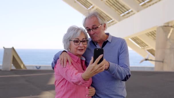 Vídeo em câmera lenta de um casal de idosos conversando durante uma videochamada com o celular em pé em um espaço urbano - Filmagem, Vídeo