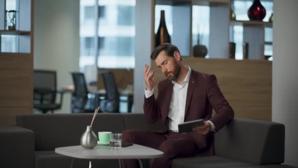 Tired employee touching face after stressful conference big corporate cabinet. Serious lawyer putting tablet computer comfortable sofa. Professional businessman thinking financial deal. Office concept - Footage, Video