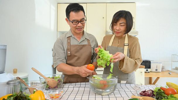 Hermosa pareja de ancianos asiáticos preparando verduras orgánicas frescas para ensalada. Concepto de alimentación saludable - Foto, imagen