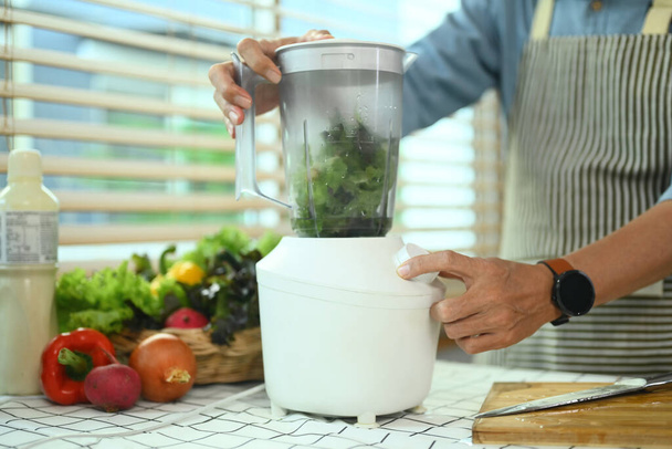 Kıdemli adam blender içinde taze sebzelerle sebze püresi yapıyor. Sağlıklı beslenme yaşam tarzı kavramı. - Fotoğraf, Görsel