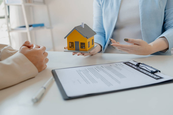 A real estate agent sits in her office, The salesperson is presenting what the home the customer is about to buy looks like, The broker is calculating the buyer's monthly instalment payments. - Photo, Image