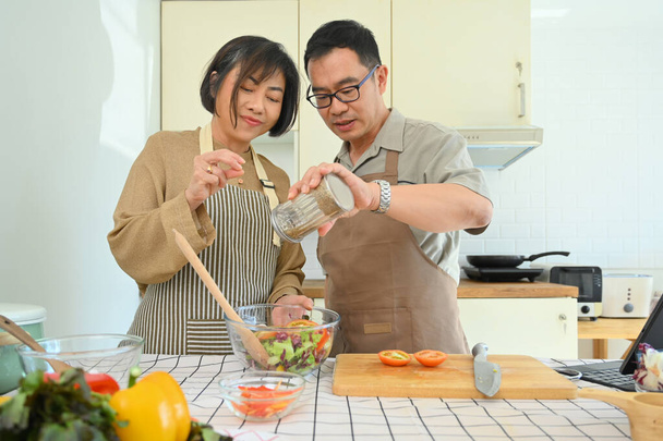 Houden van senior getrouwd stel koken gezonde vegetarische maaltijd samen in gezellige keuken. - Foto, afbeelding