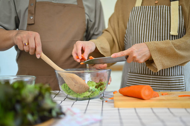 Casal sênior tiro cortado cozinhar refeição vegan saudável juntos na cozinha. Conceito de alimentação saudável - Foto, Imagem