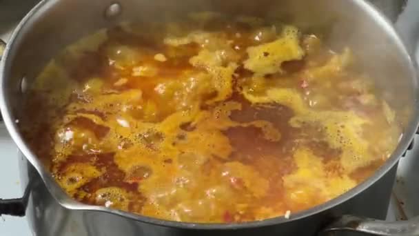 Pilaf pendant la préparation dans un pot en acier inoxydable sur le dessus de la cuisinière - Séquence, vidéo