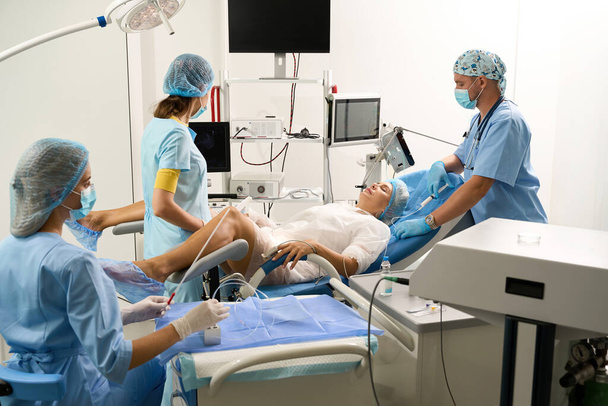 Krankenhauspersonal bei der Ultraschalluntersuchung einer schwangeren Patientin mit geschlossenen Augen vor der Geburt in der Reproduktionsklinik. Konzept von Schwangerschaft und Mutterschaft - Foto, Bild