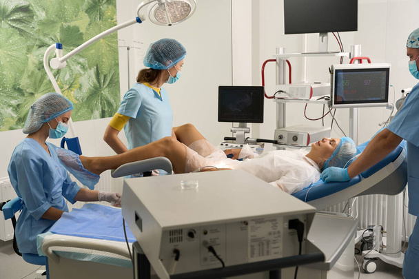 Lääkäri ja sairaanhoitajat tekevät ultraäänitutkimuksen raskaana olevalle naispotilaalle ennen synnytystä lisääntymisklinikalla. Raskauden ja äitiyden käsite - Valokuva, kuva