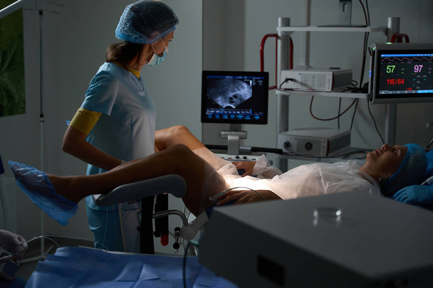 Lekarz wykonujący badanie ultrasonograficzne ciężarnej kobiety na nowoczesnym sprzęcie przed porodem w klinice rozrodczej. Pojęcie ciąży i macierzyństwa - Zdjęcie, obraz