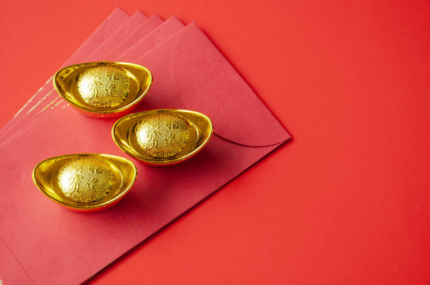 Kırmızı paketlerin üstünde altın külçe. Çin Yeni Yıl Kutlama Konsepti. - Fotoğraf, Görsel