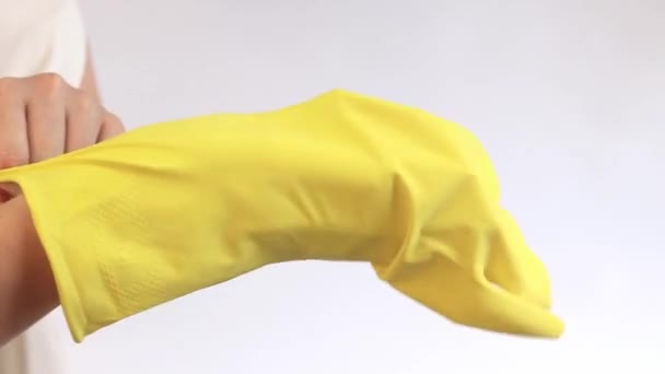 Žluté domácí rukavice. Latexové rukavice na čištění místnosti a mytí nádobí, velikost M. Dámské ruce nasazené na lehkém pozadí, čištění, detailní záběr - Záběry, video