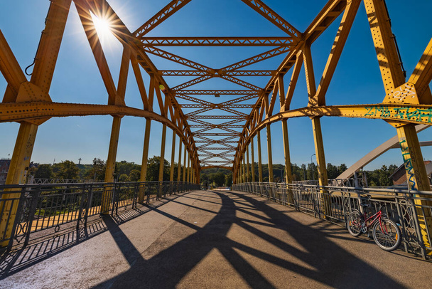 Gdaňsk, Polsko - 6. září 2023: Krásné žluté stavební pruhy litinové silnice viadukt přes kolejnice za slunečného dne se zářícím sluncem - Fotografie, Obrázek