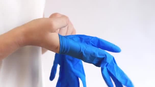 Nitrilové rukavice na čištění, jednorázové. Dámské ruce si nasadí modré rukavice na světlé pozadí, čistí, zblízka. Rukavice na ochranu rukou před vlhkostí a pracími prostředky - Záběry, video