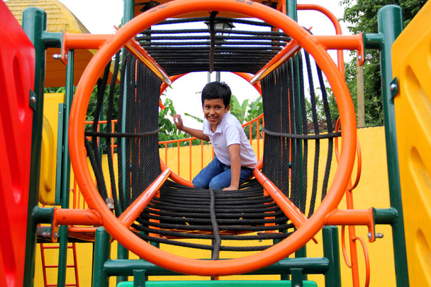 9 yaşındaki esmer tenli Latin çocuk, hiperaktivite terapisi olarak yoksulluk içinde yaşayan fiziksel bir aktivite olarak oyun bahçesinde oynuyor. - Fotoğraf, Görsel