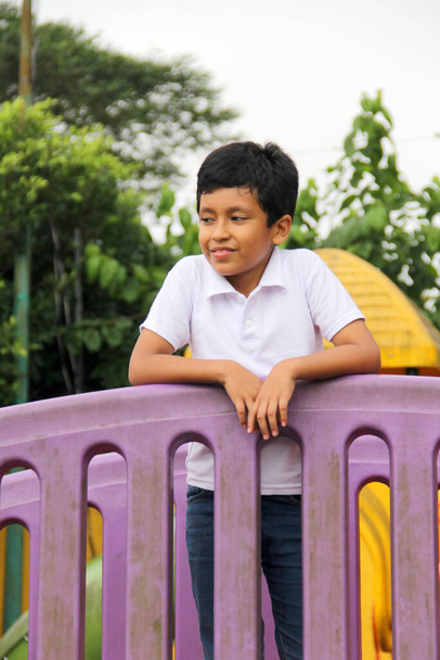 Menino latino de 9 anos de idade, de pele escura, joga em um playground como uma atividade física que vive na pobreza como terapia para TDAH - Foto, Imagem