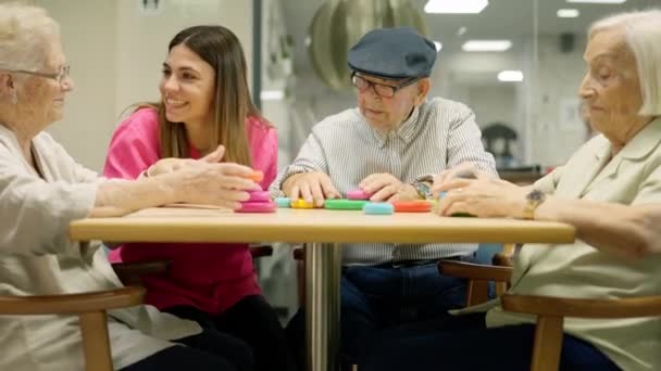 Βίντεο με τα ταξίδια επάνω από μια νοσοκόμα και ηλικιωμένους που διασκεδάζουν παίζοντας παιχνίδια δεξιοτήτων στη γηριατρική - Πλάνα, βίντεο