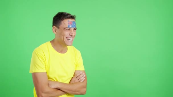 Videó a stúdióban egy boldog ember krómjával, ausztrál zászlóval az arcára festve, félrenézve az üres másolótérre. - Felvétel, videó