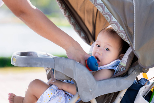 Asian Baby Boy Hydrating with a Straw from Blue Bottle, μένοντας ενυδατωμένος σε μια ζεστή μέρα σε εξωτερικούς χώρους. Ένα μικρό παιδί πεινάει και διψάει, σε μια ζεστή μέρα. Παιδί ηλικίας 1 έτους. Καλή έννοια της υγειονομικής περίθαλψης. - Φωτογραφία, εικόνα