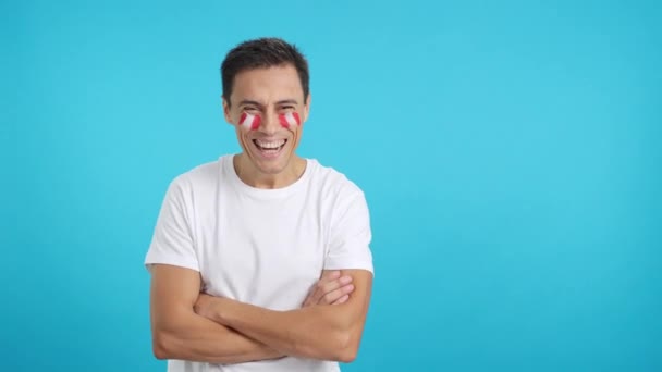 Видео в студии с хромой человека, стоящего с перуанским флагом, нарисованным на лице, улыбающимся со скрещенными руками - Кадры, видео