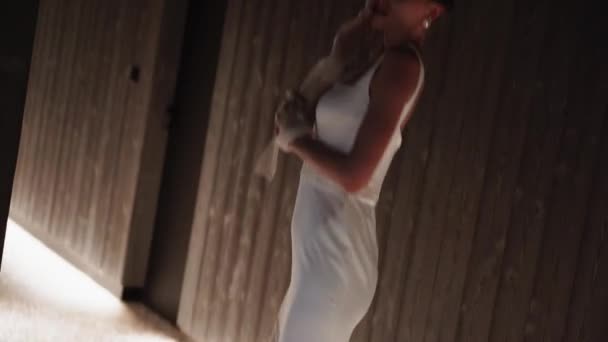 Ένα μοντέλο μόδας θέτει σε ένα λευκό φόρεμα στο διάδρομο στο φως της κάμερας. Έννοια της μόδας γυρίσματα. Μεγάλη επίδραση έκθεσης του πλαισίου. 4K - Πλάνα, βίντεο