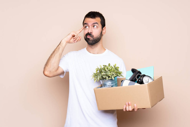 Muž držící krabici a pohybující se v novém domově na izolovaném pozadí s pochybnostmi a přemýšlením - Fotografie, Obrázek