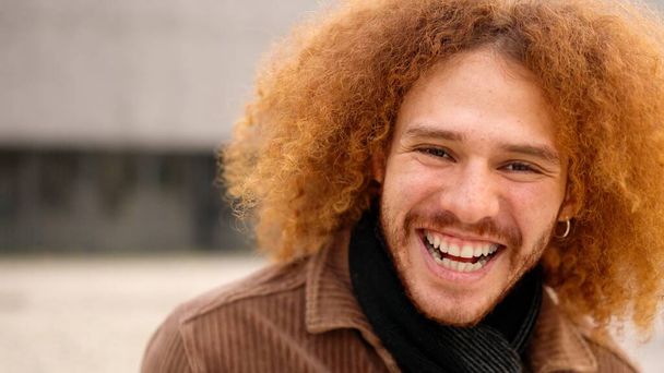 Alternativní mladý muž s kudrnatými vlasy, smějící se kameře. Zavřít - Fotografie, Obrázek