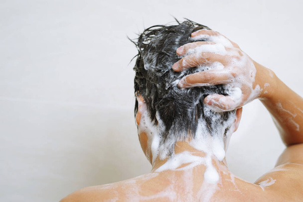 Un hombre se lava el cabello con champú. - Foto, Imagen