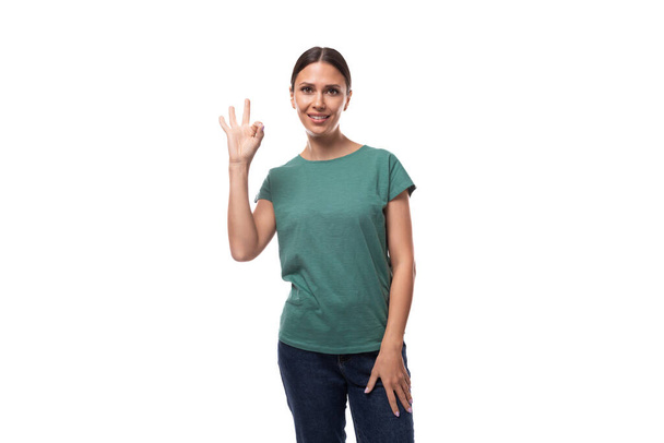 giovane donna bruna snella ben curata vestita con una t-shirt verde sorridente affabilmente. - Foto, immagini