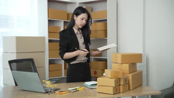 Démarrer une petite entreprise. Femme asiatique propriétaire de PME vérifie les commandes en ligne. Vente de produits qui fonctionnent avec des boîtes, freelance à la maison, entreprise de sme en ligne, petites entreprises moyennes, vidéo 4k - Séquence, vidéo