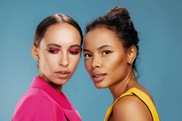 Make-up vrouw oog Afrikaanse lichaamsverzorging geel twee huid portret mooi meisje kleurrijk gezicht aantrekkelijk gezond studio gemengd ras model schoonheid samen zorg glans gelukkig amerikaans - Foto, afbeelding
