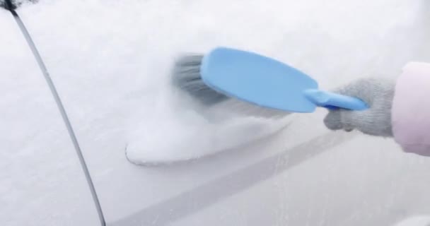 Femme nettoyant sa voiture de la neige avec une brosse. Images 4k de haute qualité - Séquence, vidéo