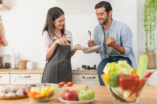 Счастливая молодая пара готовит вместе в кухонном столе дома - Фото, изображение