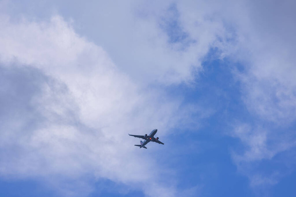 Прекрасный вид на посадочный самолет с включенным светом на фоне голубого неба с белыми облаками. США. - Фото, изображение