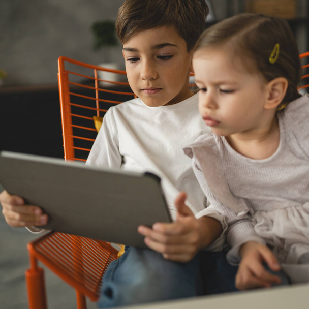 Брат и сестра маленькие дети братья и сестры использовать цифровой планшет на дому смотреть онлайн видео - Фото, изображение