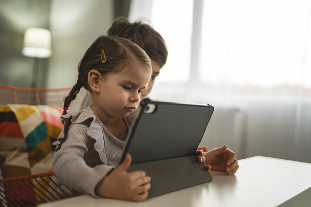 Brat i siostra małe dzieci rodzeństwo korzystać z tabletu cyfrowego w domu oglądać wideo online - Zdjęcie, obraz