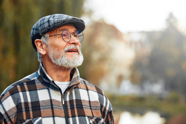 Hezký dědeček zralý šedovlasý muž v kostkované košili a brýlích stojící v parku na podzim. - Fotografie, Obrázek