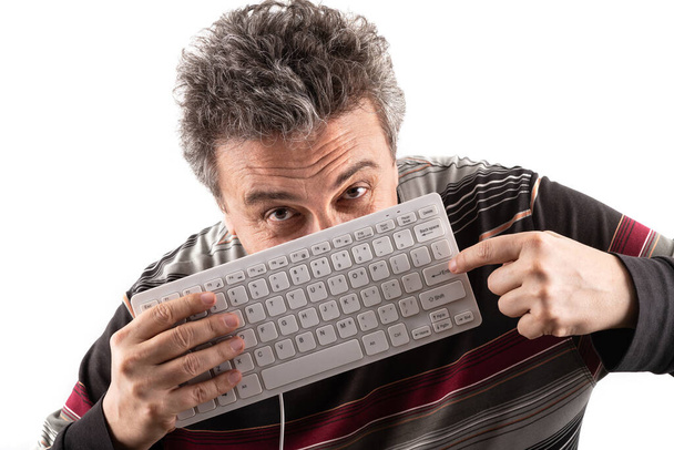 Orta yaşlı bir adam bilgisayar klavyesinin arkasından dışarı bakar. - Fotoğraf, Görsel