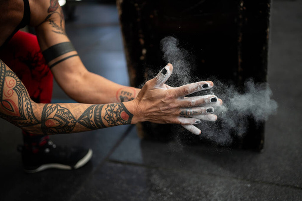 Крупный план женской сильной руки с магниевым зажимом, готовой к тяжелой атлетике в тренажерном зале - Фото, изображение