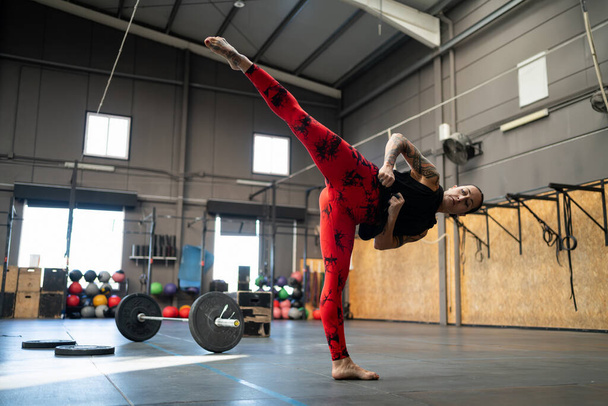 Horizontal photo with copy space of a sportive woman kicking in the air in a gym - Photo, Image